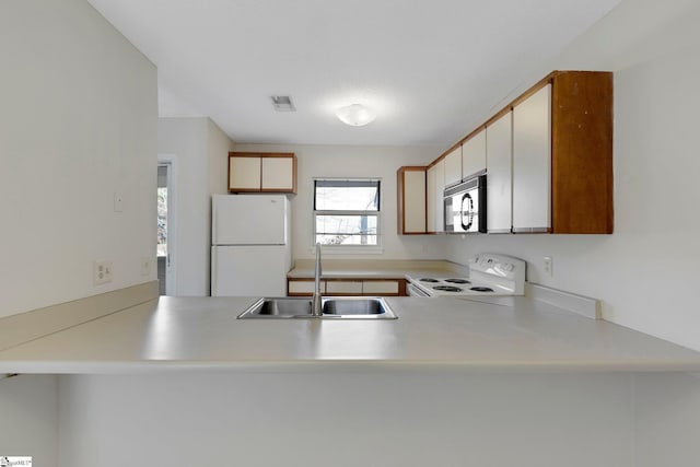 kitchen with kitchen peninsula, white appliances, and sink