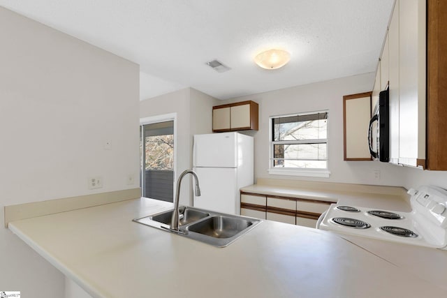 kitchen with white refrigerator, electric stove, sink, a textured ceiling, and kitchen peninsula