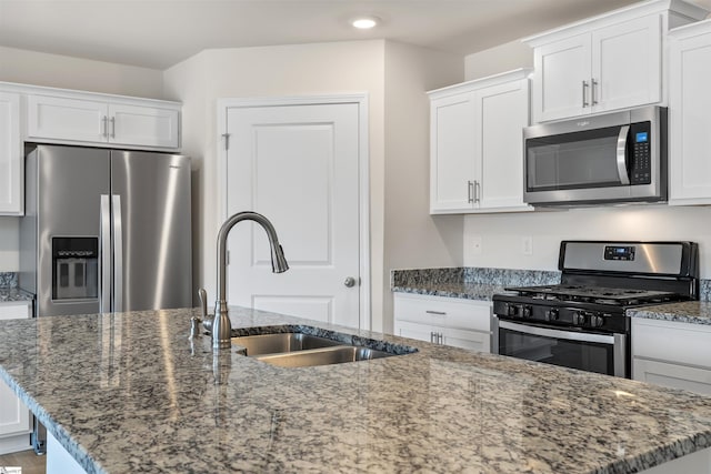 kitchen with appliances with stainless steel finishes, white cabinetry, and a kitchen island with sink