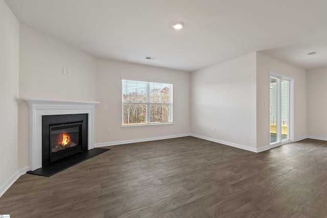 unfurnished living room featuring plenty of natural light and dark hardwood / wood-style flooring