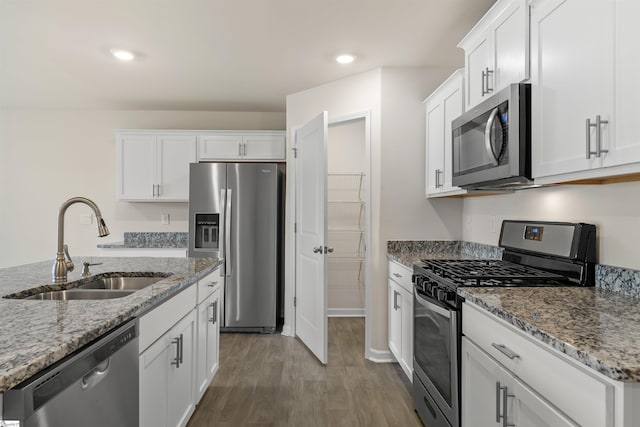 kitchen featuring light stone counters, stainless steel appliances, dark wood-type flooring, sink, and white cabinets