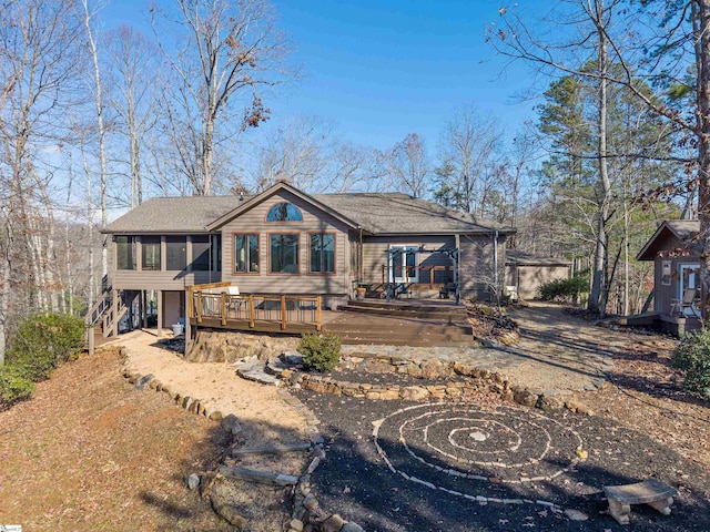 rear view of property featuring a sunroom and a wooden deck