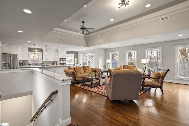 living room with a tray ceiling, ceiling fan, wood-type flooring, and ornamental molding