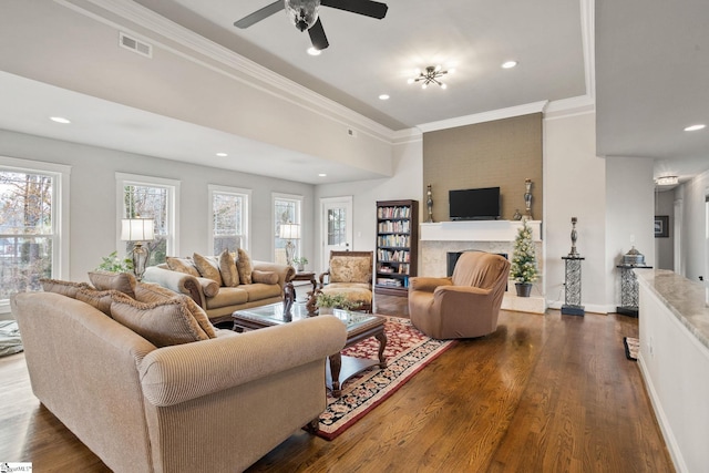 living room featuring a fireplace, dark hardwood / wood-style floors, ceiling fan, and ornamental molding