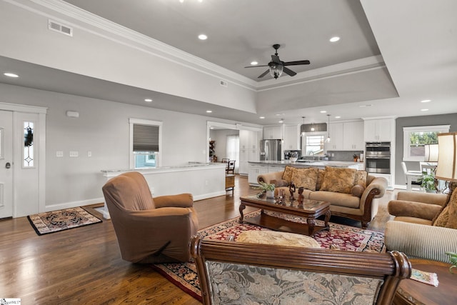 living room featuring ceiling fan, crown molding, dark wood-type flooring, and sink