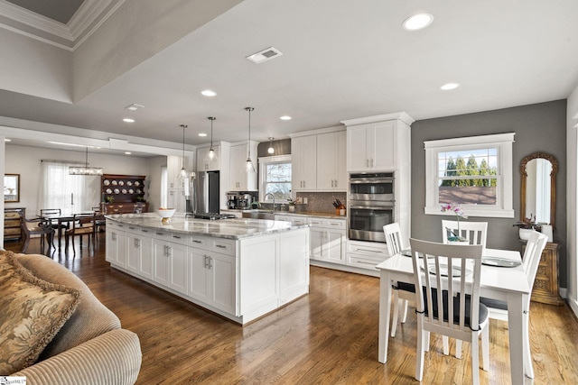 kitchen featuring light stone counters, a kitchen island, dark hardwood / wood-style floors, white cabinetry, and hanging light fixtures