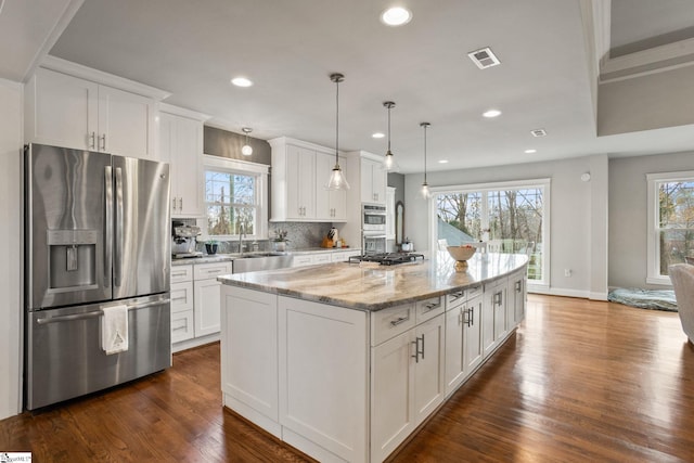 kitchen with plenty of natural light, white cabinets, stainless steel appliances, and a kitchen island