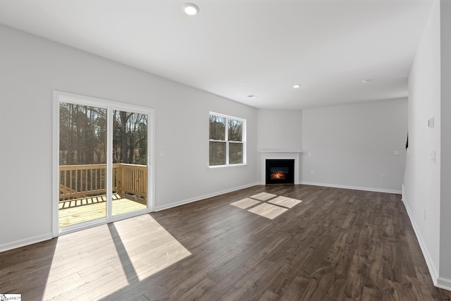 unfurnished living room featuring a glass covered fireplace, recessed lighting, dark wood-style floors, and baseboards