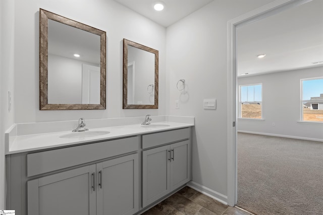 full bathroom featuring double vanity, baseboards, and a sink