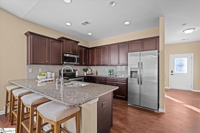 kitchen featuring dark hardwood / wood-style floors, decorative backsplash, kitchen peninsula, and appliances with stainless steel finishes