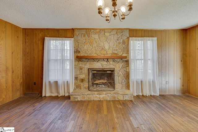 unfurnished living room with wood-type flooring, wooden walls, and a healthy amount of sunlight