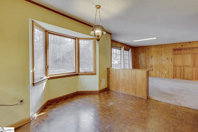 unfurnished room with wood walls, parquet flooring, and a textured ceiling