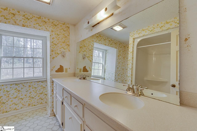 bathroom featuring tile patterned flooring, vanity, a healthy amount of sunlight, and a textured ceiling