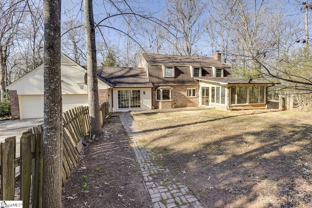 view of front of property with a sunroom, a front lawn, and a garage