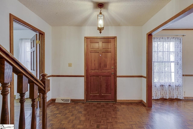 foyer featuring dark parquet floors and a textured ceiling