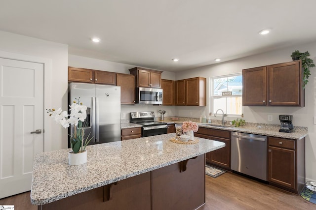 kitchen with sink, a kitchen breakfast bar, light hardwood / wood-style floors, a kitchen island, and appliances with stainless steel finishes