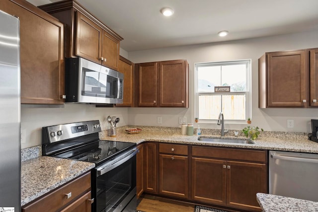 kitchen with dark hardwood / wood-style floors, light stone counters, sink, and appliances with stainless steel finishes