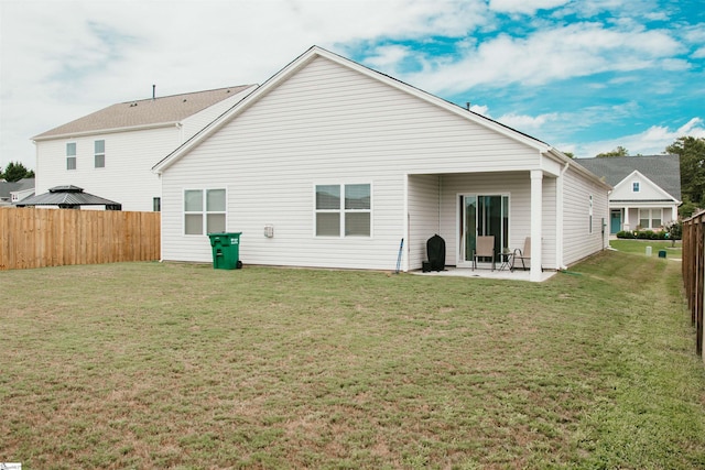 rear view of house featuring a lawn and a patio