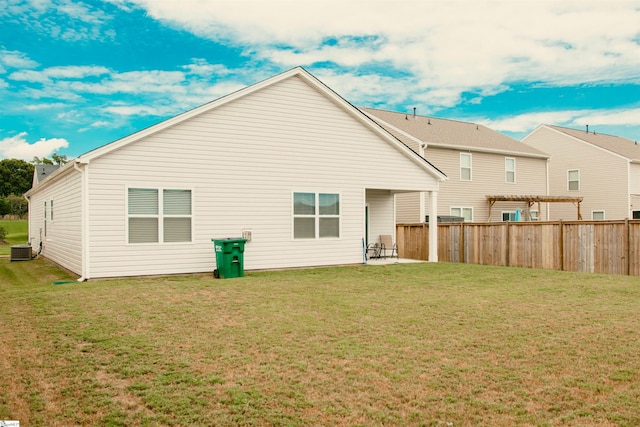 rear view of property featuring a patio, a yard, and central AC