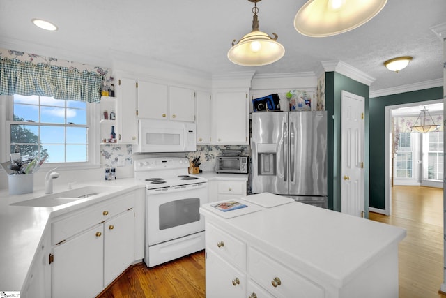 kitchen with white cabinetry, a wealth of natural light, decorative light fixtures, and white appliances