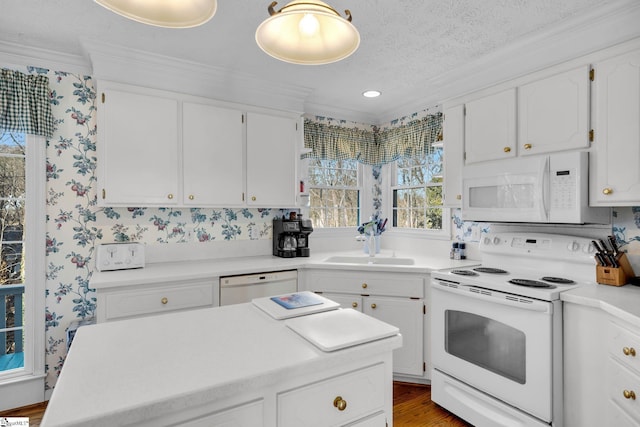 kitchen featuring a textured ceiling, white appliances, crown molding, hardwood / wood-style floors, and white cabinetry