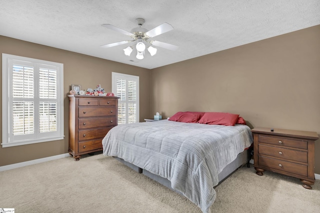 bedroom with ceiling fan, light colored carpet, and a textured ceiling