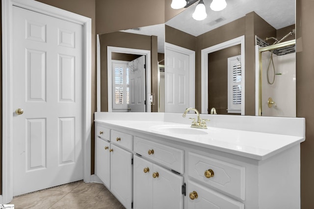 bathroom with tile patterned flooring, vanity, and walk in shower