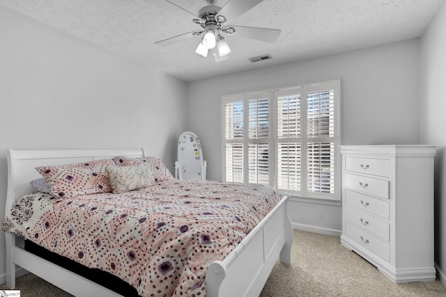 bedroom featuring ceiling fan, light colored carpet, and a textured ceiling