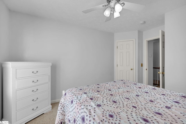 bedroom with ceiling fan, light colored carpet, and a textured ceiling