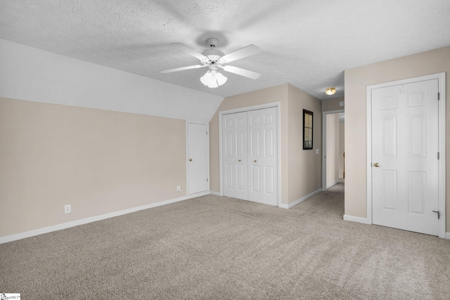 unfurnished bedroom featuring ceiling fan, a textured ceiling, light carpet, and vaulted ceiling