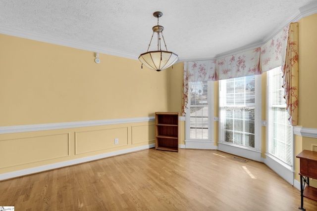 unfurnished dining area with hardwood / wood-style flooring, a healthy amount of sunlight, and ornamental molding