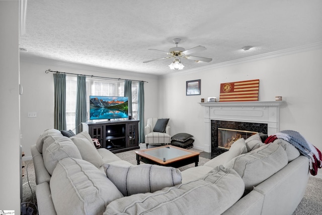 carpeted living room with a premium fireplace, ceiling fan, a textured ceiling, and ornamental molding