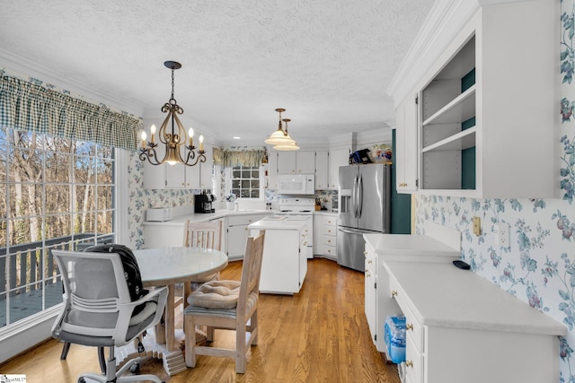 kitchen featuring white cabinetry, a center island, an inviting chandelier, decorative light fixtures, and white appliances