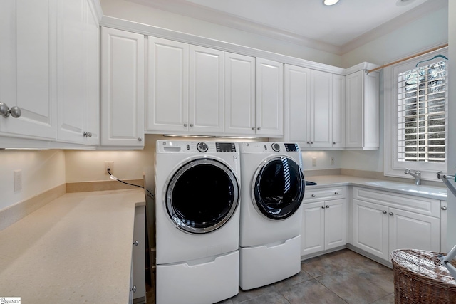 clothes washing area featuring cabinets, crown molding, sink, light tile patterned floors, and washing machine and clothes dryer