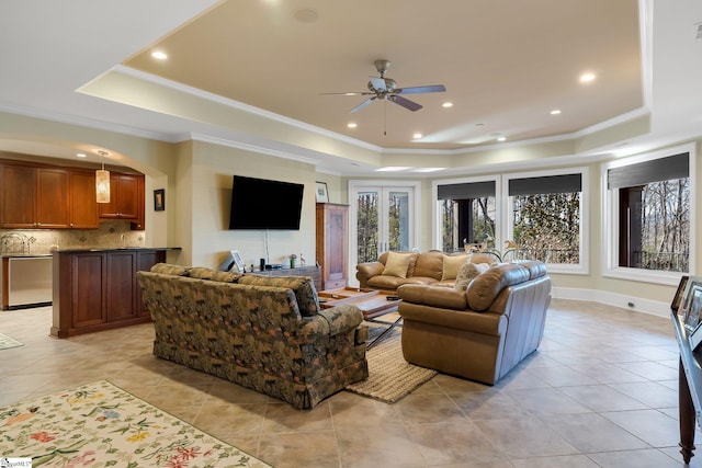 living room with ceiling fan, ornamental molding, light tile patterned floors, and a tray ceiling