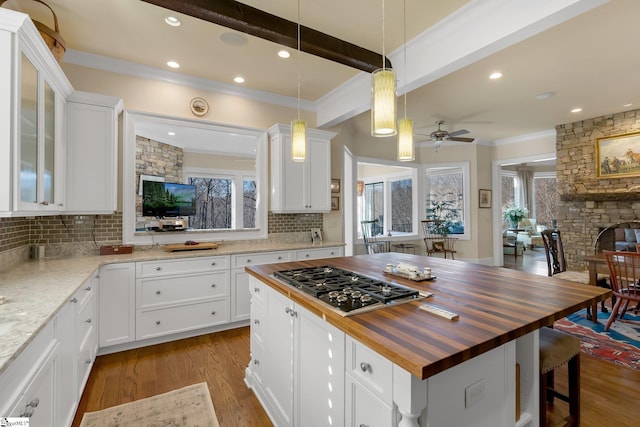 kitchen featuring wooden counters, a center island, white cabinetry, and stainless steel gas stovetop