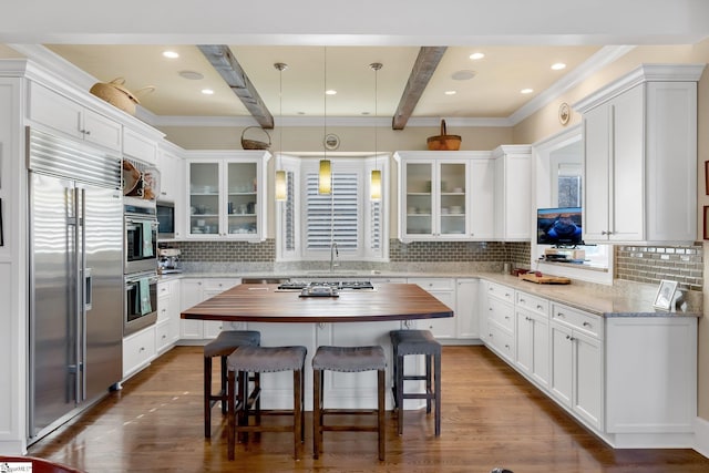 kitchen featuring wooden counters, appliances with stainless steel finishes, backsplash, beam ceiling, and decorative light fixtures