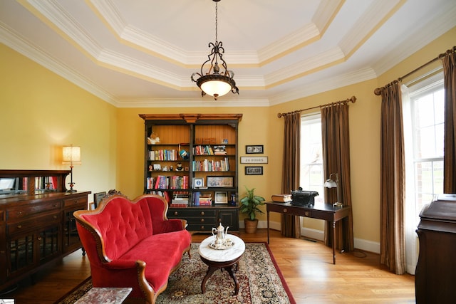 sitting room featuring a raised ceiling, light hardwood / wood-style flooring, and ornamental molding