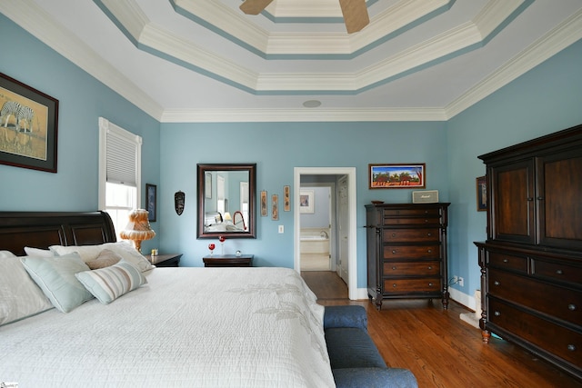 bedroom featuring ensuite bathroom, ornamental molding, a tray ceiling, ceiling fan, and dark wood-type flooring