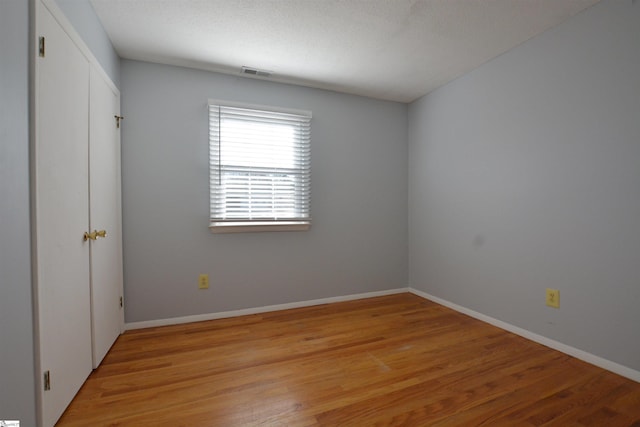 unfurnished room with a textured ceiling and light hardwood / wood-style flooring