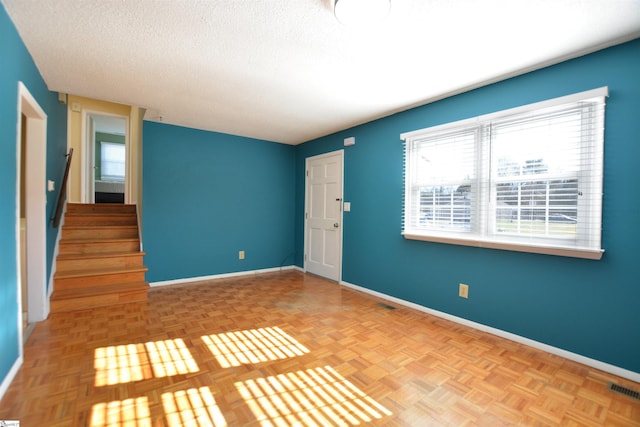 unfurnished room featuring a textured ceiling and light parquet floors