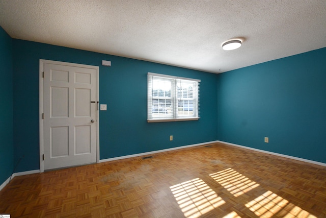 empty room with parquet flooring and a textured ceiling