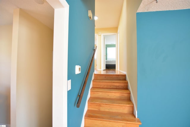 stairway with hardwood / wood-style floors and a textured ceiling