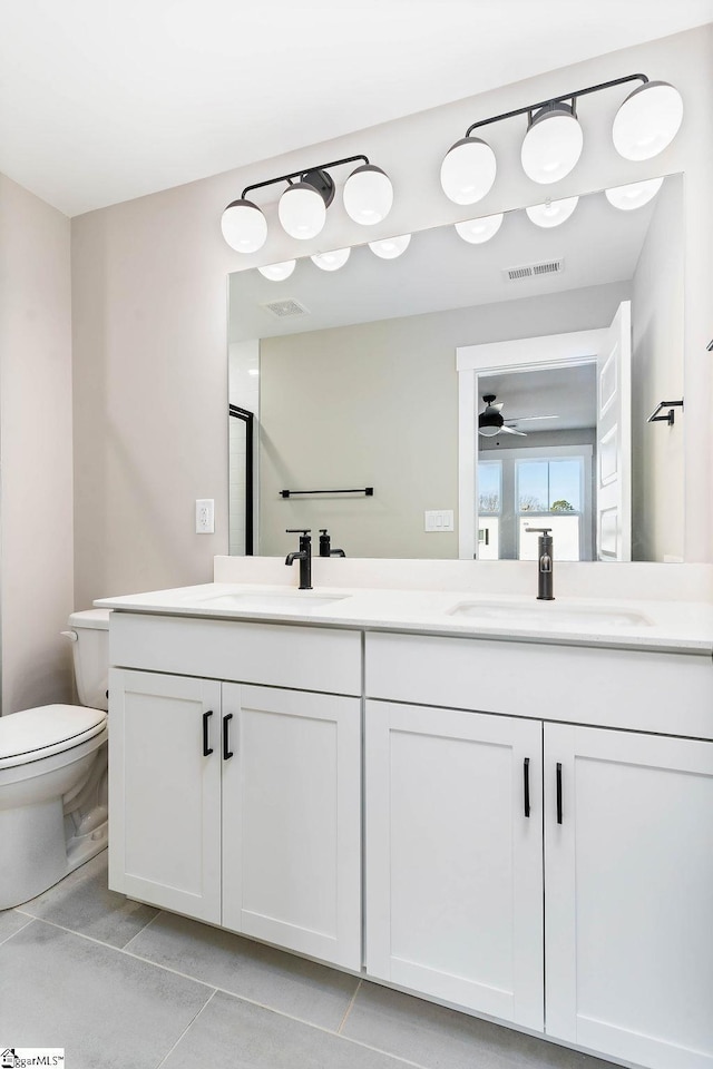bathroom with tile patterned flooring, vanity, a shower with door, and toilet