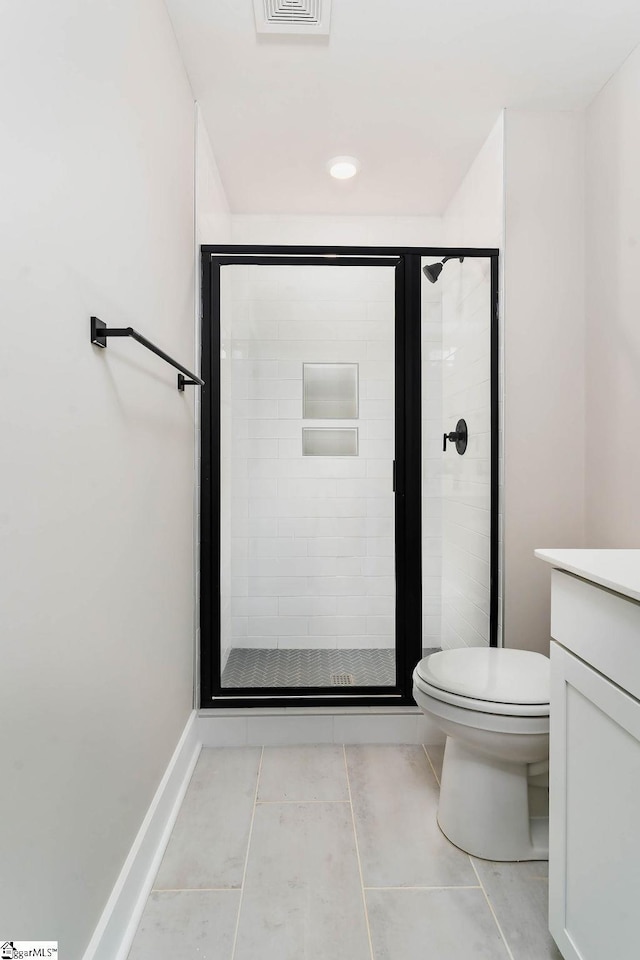 bathroom featuring tile patterned floors, vanity, toilet, and a shower with shower door