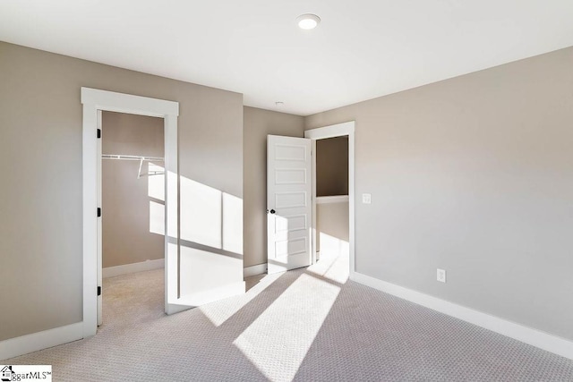 unfurnished bedroom with light colored carpet, a closet, and a walk in closet