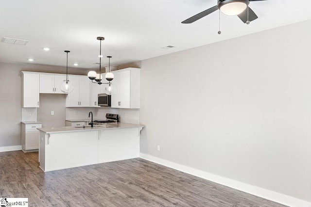 kitchen featuring pendant lighting, white cabinetry, decorative backsplash, light hardwood / wood-style floors, and stainless steel appliances