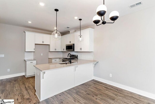kitchen with hanging light fixtures, appliances with stainless steel finishes, sink, and white cabinets
