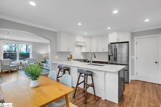 kitchen with sink, stainless steel fridge with ice dispenser, kitchen peninsula, extractor fan, and white cabinets