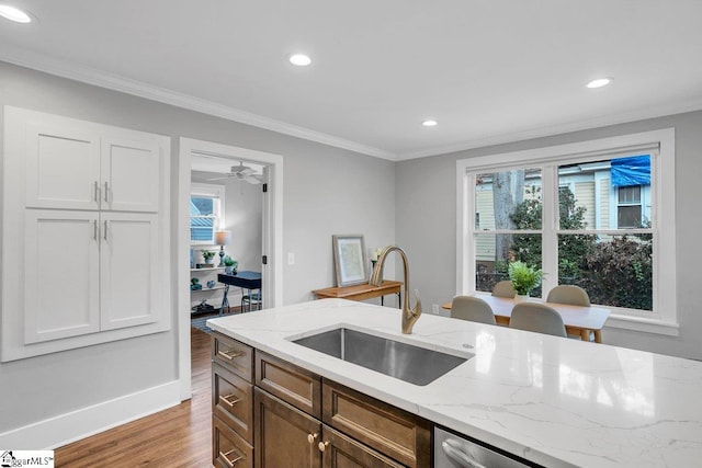 kitchen with light stone countertops, sink, white cabinets, and light hardwood / wood-style flooring